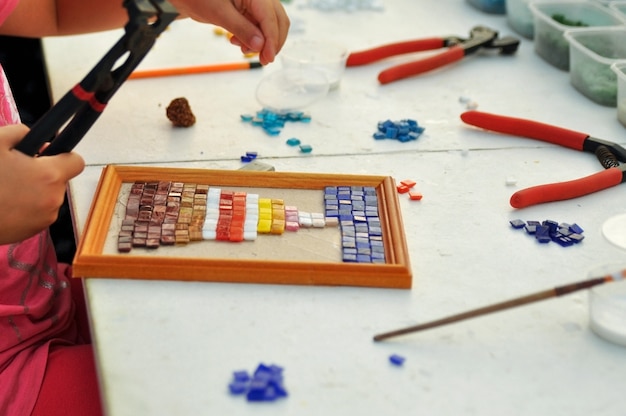 L'enfant fait un panneau de mosaïque de verre coloré