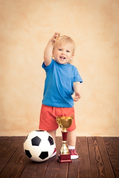 L'enfant fait semblant d'être un joueur de football. Concept de réussite et de gagnant