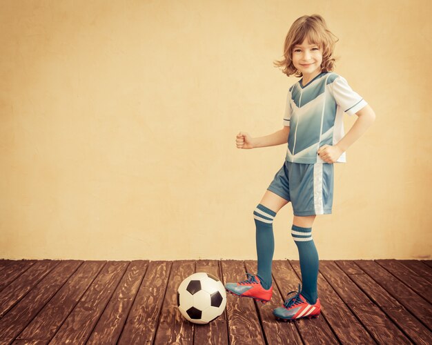 L'enfant fait semblant d'être un joueur de football. Concept de réussite et de gagnant