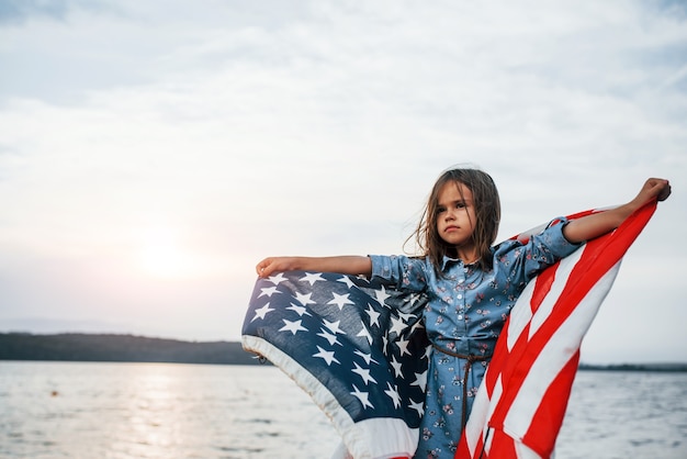 Enfant femelle patriotique avec le drapeau américain dans des mains