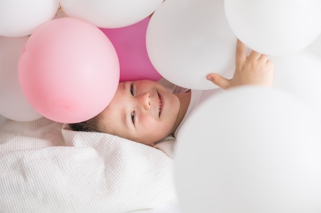 enfant fête son anniversaire sur fond blanc avec de nombreux ballons