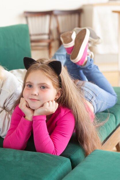 Enfant fille allongée sur le canapé sur sa tête oreilles de chat noir concept d'enfance et de carnaval