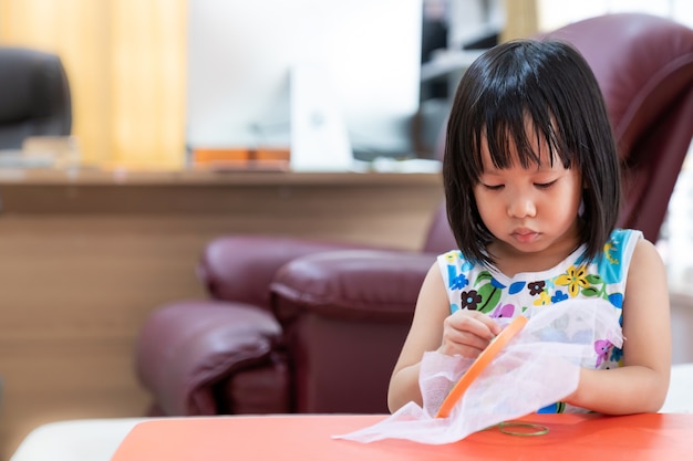 Enfant fille asiatique couture dans le salon à la maison comme enseignement à domicile