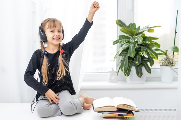 enfant fille aux cheveux blonds dans les écouteurs écoute de la musique. la distance sociale. quarantaine et épidémie.