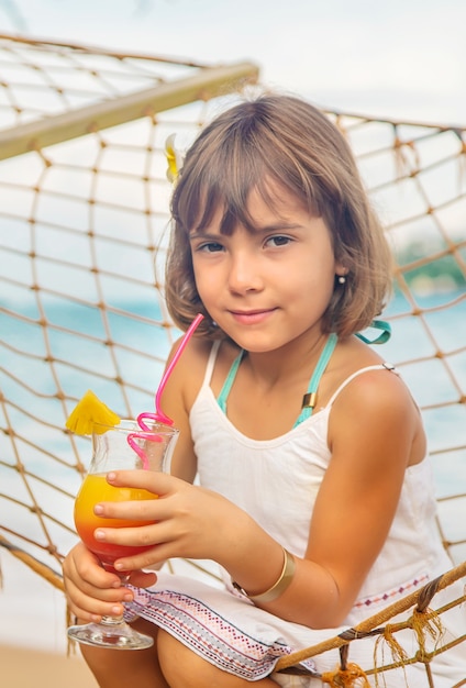 Enfant fille boit un cocktail sur la plage