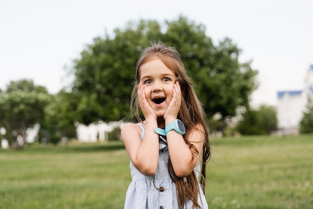 Enfant fille choquée dans le parc Adorable enfant surpris touche ses joues