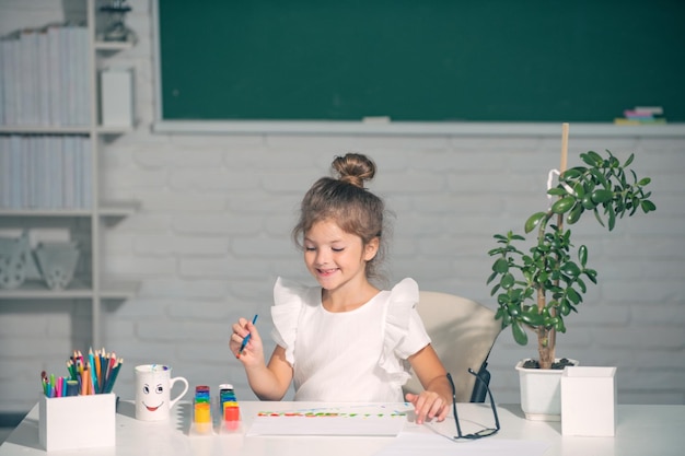 Enfant fille à l'école dessine avec des peintures enfants artiste créativité drôle enfants visage