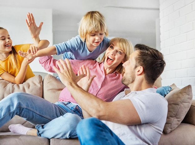 Enfant fille fils famille heureuse mère père canapé jouant ensemble amusant fille garçon joyeux souriant accueil