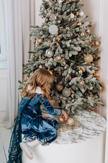 Enfant fille habillée décore des boules de sapin de Noël