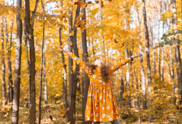 Enfant fille jetant des feuilles d'automne sur l'automne nature plaisir loisirs et concept d'enfance