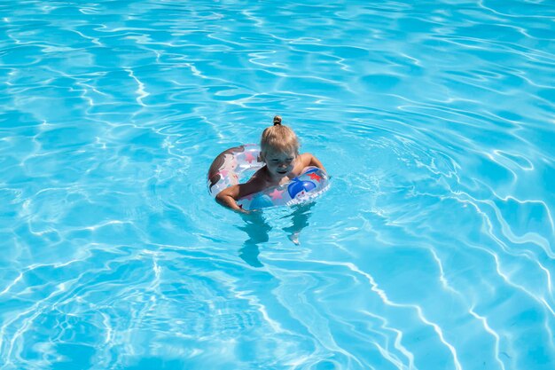 Enfant fille nage avec un anneau gonflable dans la piscine vue de dessus mise à plat