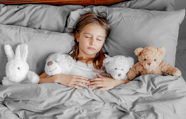 Enfant fille avec ours en peluche dans le lit