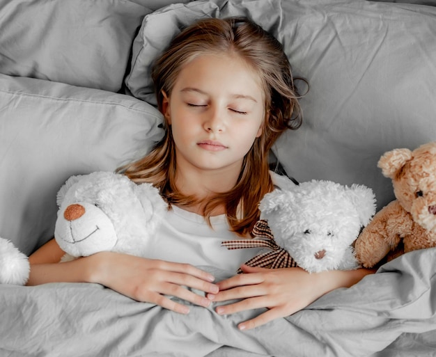 Enfant fille avec ours en peluche dans le lit