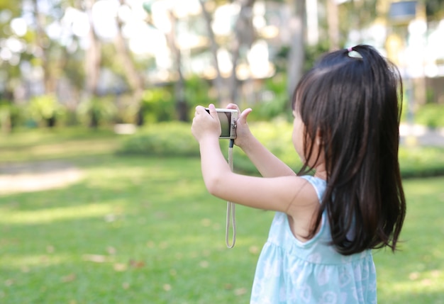 Enfant fille prenant des photos sur l&#39;appareil photo dans le jardin