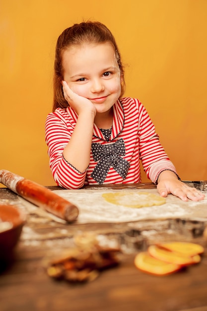 enfant, fille prépare la pâte à biscuits sur un fond en bois