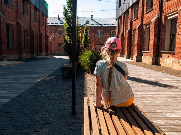 Enfant fille se repose dans un café moderne de style loft Zone de détente murs de briques rouges Rénovation de bâtiments anciens Espace de travail extérieur Espace urbain créatif Maçonnerie de ville Conception d'entrepôt Fenêtres du sol au plafond