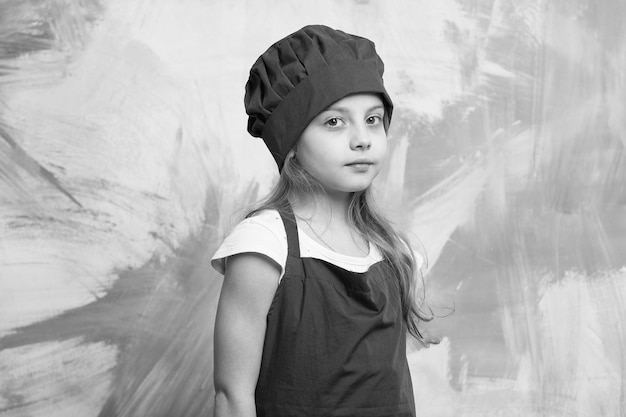 Enfant fille sérieuse cuisinier en tablier de toque rouge