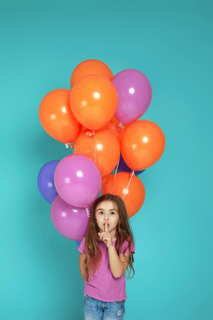 Enfant fille en t-shirt rose posant avec des ballons à air colorés lumineux