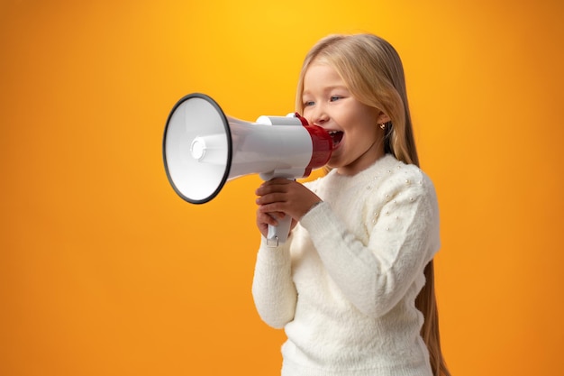 Enfant fille utilisant un mégaphone sur fond jaune