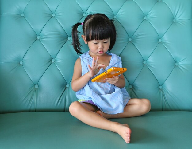 Enfant Fille Utilisant Un Téléphone Intelligent Sur Un Canapé Vintage