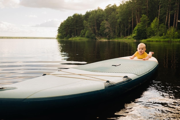 L'enfant flotte sur l'eau sur une grande planche de sup Sports nautiques