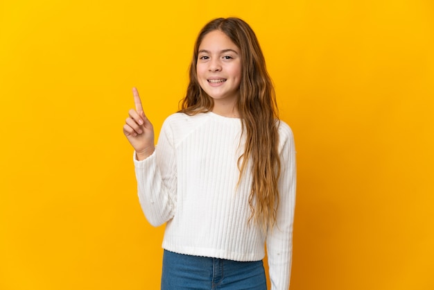 Enfant sur fond jaune isolé montrant et levant un doigt en signe du meilleur