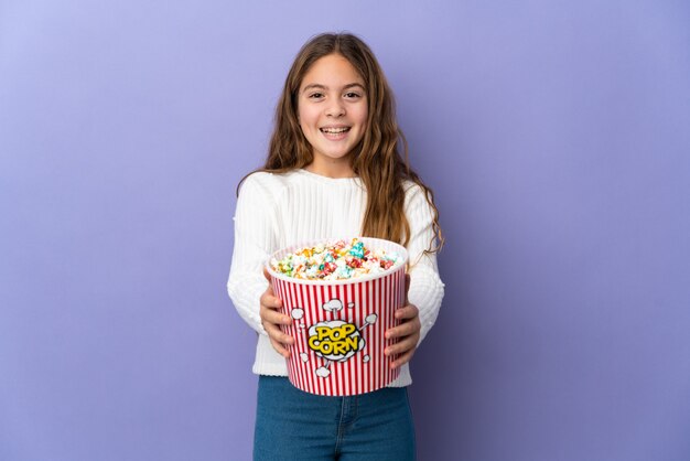 Enfant sur fond violet isolé tenant un grand seau de pop-corn