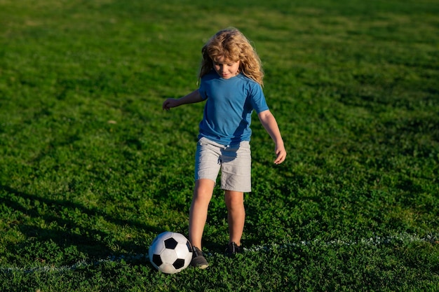 Un enfant de football joue au football un enfant qui frappe un ballon de football sur un enfant de sports d'herbe pendant l'entraînement de football