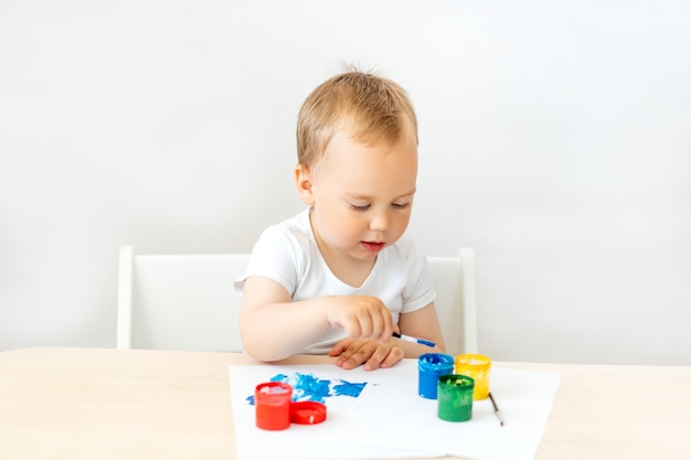 Enfant garçon 2 ans assis à une table sur blanc