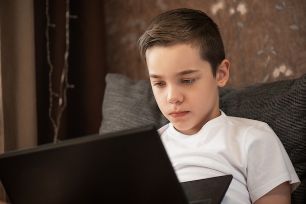 Enfant garçon ou adolescent apprenant à la maison sur un ordinateur portable pour l'école