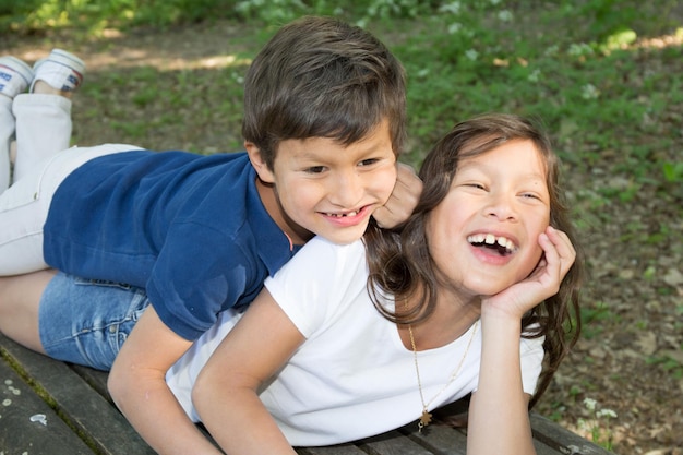 Enfant garçon allongé dans l'herbe avec sa soeur dans le parc