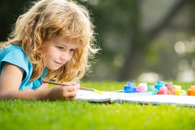 Enfant garçon appréciant l'art et l'artisanat dessinant dans l'arrière-cour ou le parc de printemps