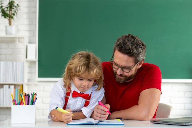 Enfant garçon apprenant avec l'enseignant petit garçon drôle étudier avec le père en classe sur tableau noir enfant de e