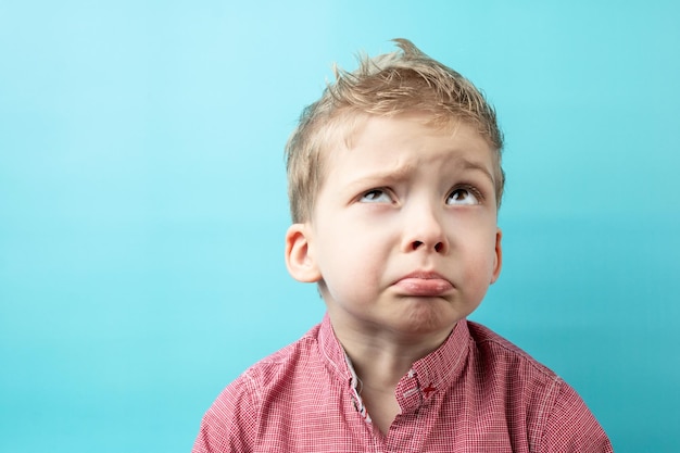 Enfant garçon en chemise rouge sur fond bleu