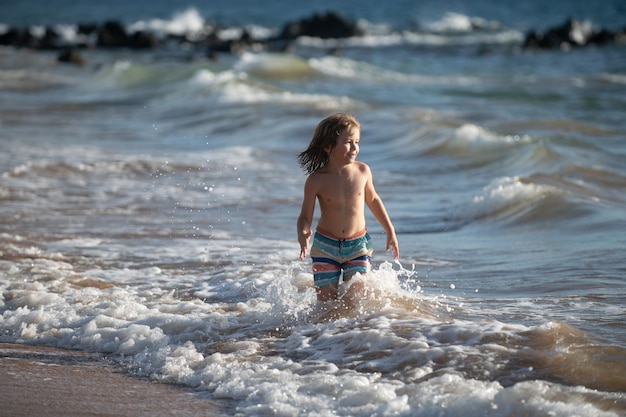 Enfant garçon sur la côte petit enfant jouant dans l'océan vacances sur la mer l'enfant dans les vagues