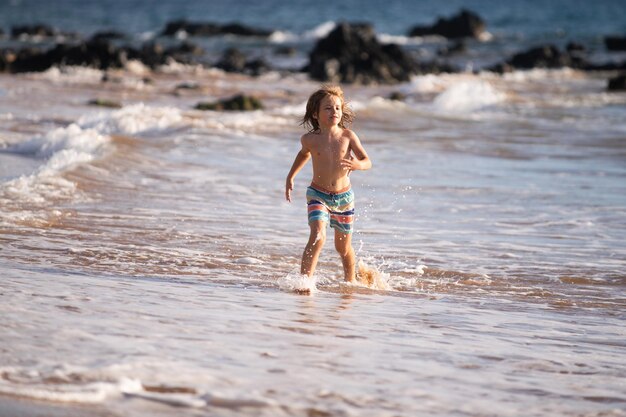 Enfant garçon sur la côte petit enfant jouant dans l'océan vacances sur la mer l'enfant dans les vagues