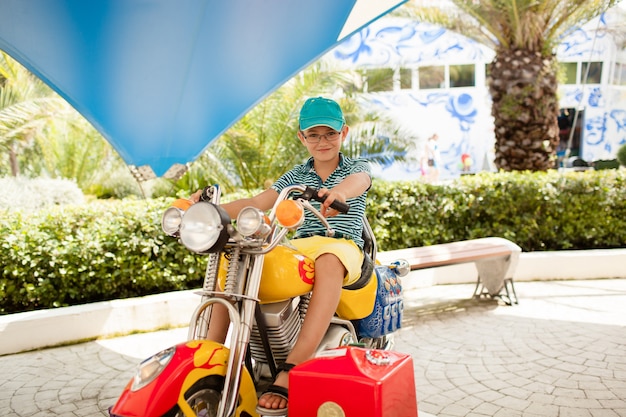 Enfant garçon dans un parc d'attractions sur une moto