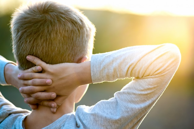 Enfant garçon debout à l'extérieur par une journée ensoleillée d'été bénéficiant d'un temps chaud à l'extérieur. Concept de repos et de bien-être.