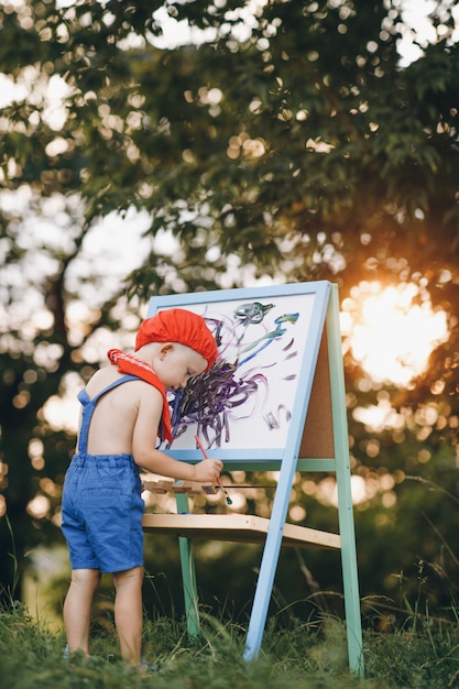 Photo enfant garçon dessin photo à l'extérieur dans le parc d'été