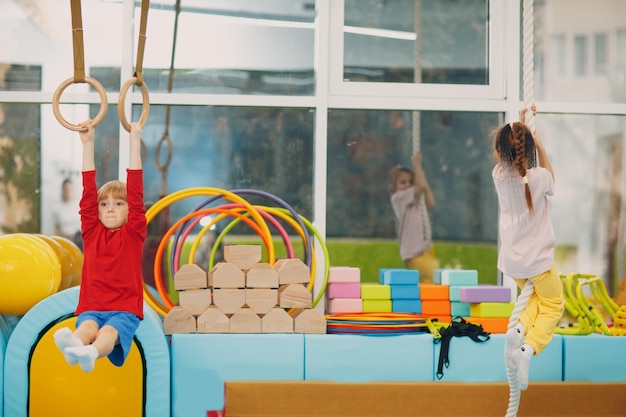 Enfant garçon faisant des exercices dans la salle de gym à la maternelle ou à l'école primaire Enfants sport et fitness sport anneaux concept