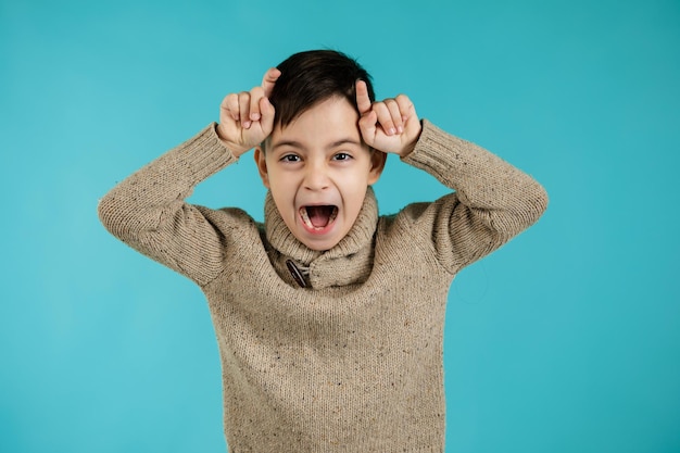 Enfant garçon faisant un geste drôle avec le doigt sur la tête comme des cornes de taureau