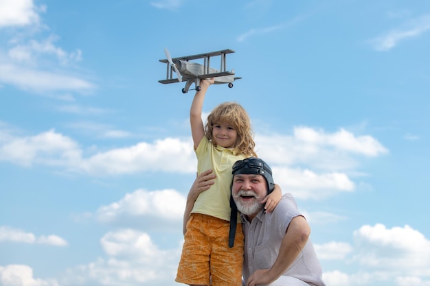 Enfant garçon et grand-père avec avion jetpack jouet contre ciel enfant pilote aviateur avec avion rêves o...