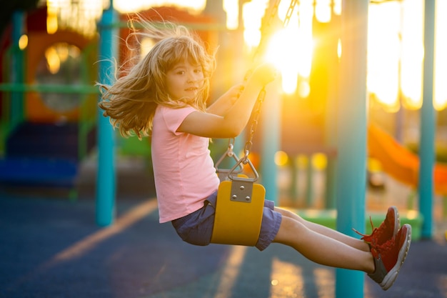 Enfant garçon jouant à l'aire de jeux pour enfants Petit enfant actif sur l'aire de jeux Les enfants jouent à l'école ou à la maternelle Enfant actif sur une balançoire colorée Petit garçon se balançant