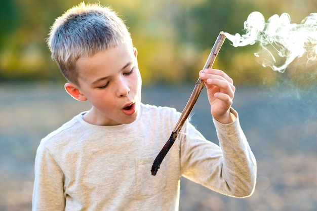 Enfant garçon jouant avec le tabagisme en bois à l'extérieur.