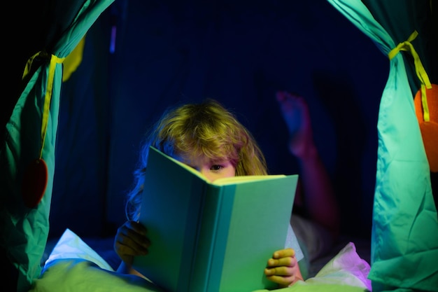 Enfant garçon lisant des livres Visage d'enfant avec veilleuse Concept d'éducation et de lecture Développement de l'imagination des enfants