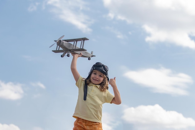 Enfant garçon avec lunettes de pilote et casque jouant avec un avion jouet en bois rêve de devenir pilote Rêves d'enfants Enfant pilote aviateur avec avion en bois Été à la campagne