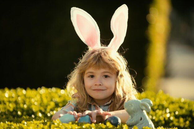 Enfant garçon avec des oeufs de pâques chasse aux oeufs de pâques en plein air fynny enfants face joyeux jour de pâques enfant avec lapin