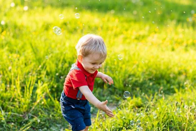 Enfant garçon s'amuse à jouer dans la nature avec des bulles de savon brillantes