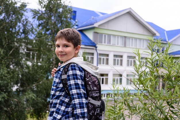 Enfant garçon avec sac reste près de l'école primaire