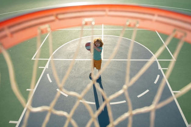 Enfant garçon se préparant au tir de basket-ball en plein air sur l'aire de jeux